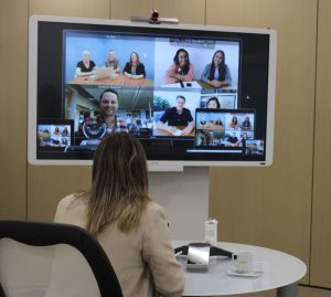 Persona trabajando en videollamada con proyector y medios audiovisuales
