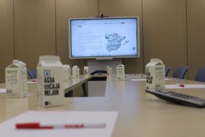 Sala de reuniones tecnológica con pantalla tactil, boligrafos y botellas de agua